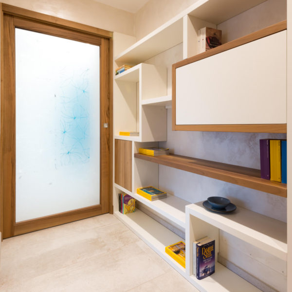 Porta scorrevole  in noce nazionale con libreria su misura