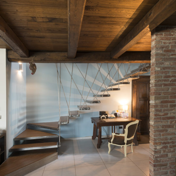 Scala su misura con pedate in frassino e struttura portante in acciaio inox spazzolato. Soffitto in castagno